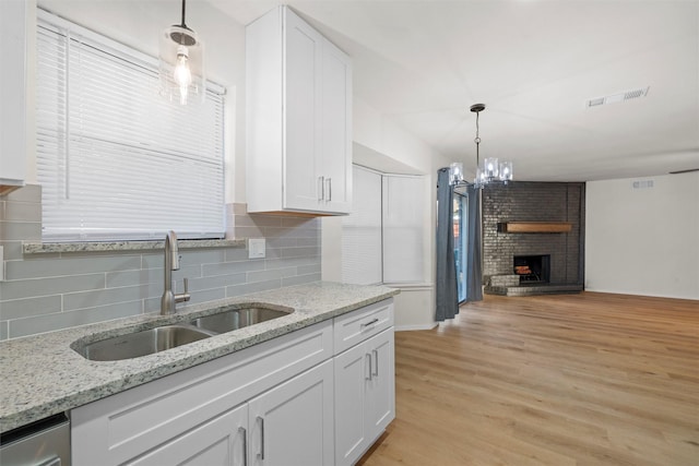 kitchen with visible vents, open floor plan, light wood-type flooring, white cabinets, and a sink