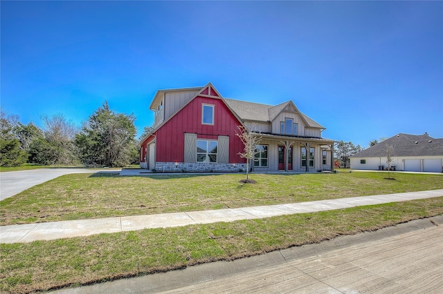 view of front of property with board and batten siding, driveway, a barn, a front yard, and a garage