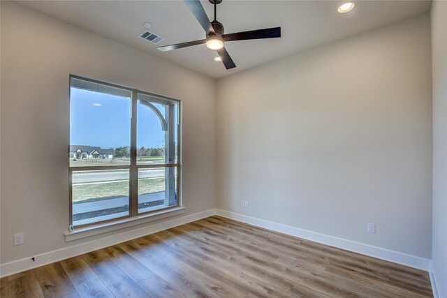unfurnished room featuring a ceiling fan, wood finished floors, baseboards, and visible vents