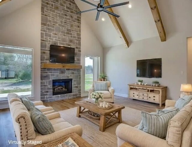 living area with high vaulted ceiling, beam ceiling, a ceiling fan, a fireplace, and wood finished floors