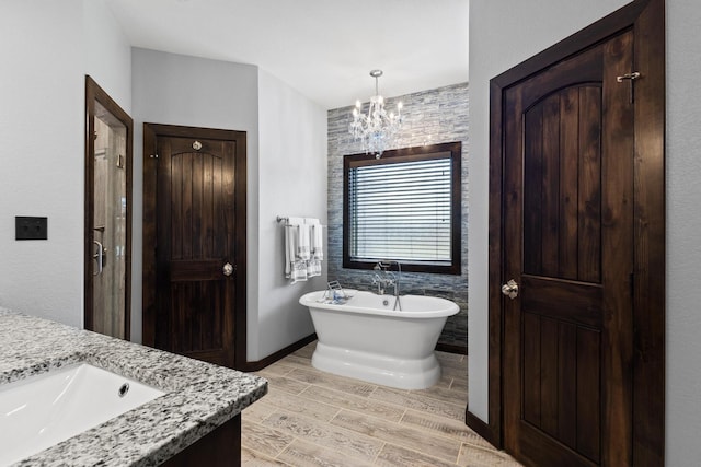 full bathroom featuring vanity, a stall shower, a chandelier, a freestanding bath, and wood finished floors