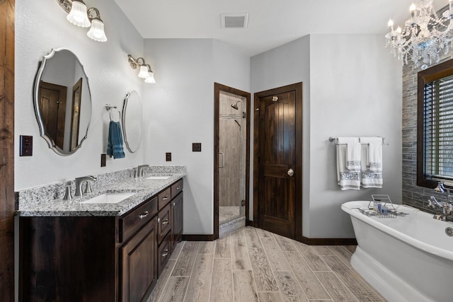 full bath with a sink, visible vents, a freestanding tub, and wood finished floors