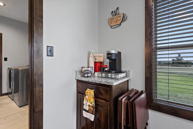 bar featuring washing machine and clothes dryer, light wood-type flooring, and a healthy amount of sunlight