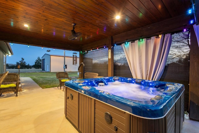 view of patio with a hot tub and an outbuilding