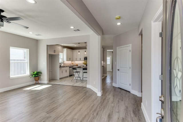 kitchen featuring decorative light fixtures, appliances with stainless steel finishes, white cabinets, backsplash, and a sink