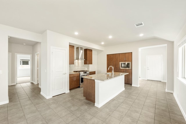 3255 Blossom Trl, Crandall, TX 75114 - kitchen featuring wall chimney range hood, stainless steel appliances, brown cabinetry, a sink, and an island with sink
