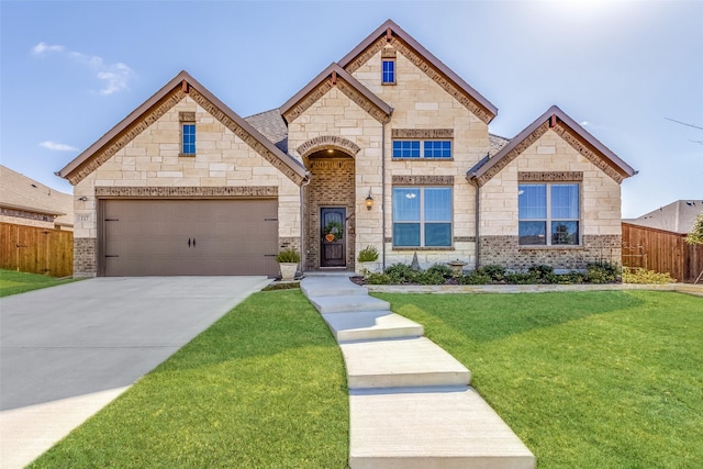 french provincial home featuring stone siding, driveway, a front yard, and fence