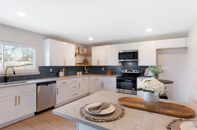 kitchen with open shelves, a sink, stainless steel appliances, white cabinets, and tasteful backsplash