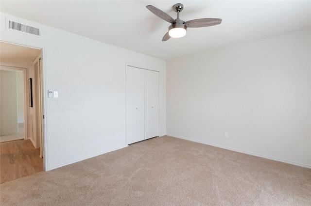 unfurnished bedroom featuring a closet, visible vents, a ceiling fan, and carpet