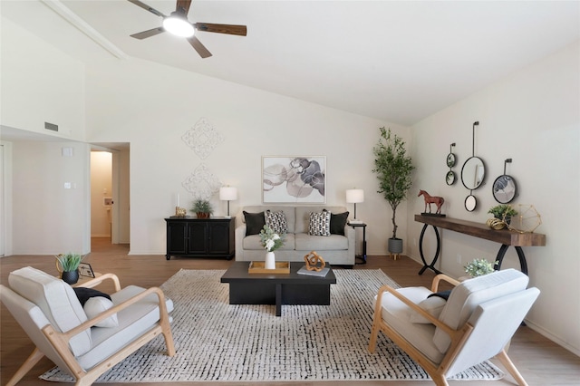 living room featuring light wood finished floors, visible vents, a ceiling fan, and vaulted ceiling