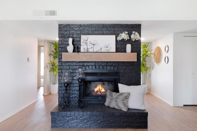 room details with wood finished floors, a fireplace, visible vents, and baseboards
