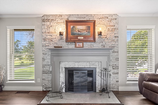 details featuring wood finished floors, baseboards, visible vents, a fireplace, and ornamental molding