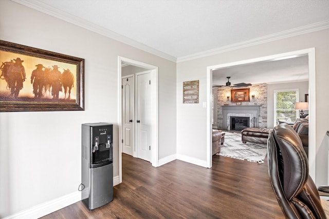 interior space featuring dark wood finished floors, a large fireplace, ceiling fan, and ornamental molding
