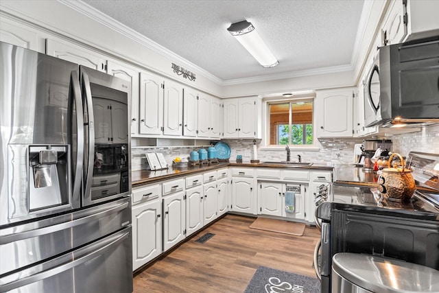 kitchen featuring crown molding, appliances with stainless steel finishes, dark wood-style floors, white cabinets, and a sink