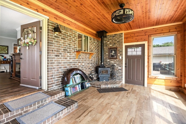 foyer entrance featuring ornamental molding, wooden ceiling, a wood stove, and wood-type flooring