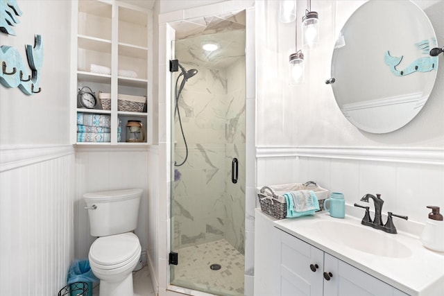 full bathroom featuring vanity, toilet, a marble finish shower, and wainscoting