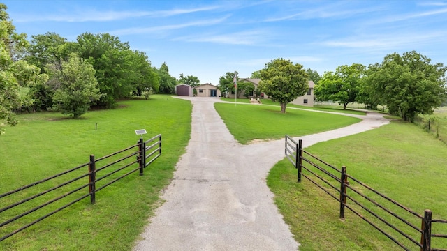 surrounding community featuring a rural view, a yard, fence, and driveway