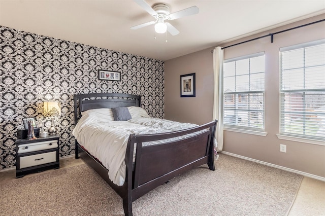 carpeted bedroom featuring baseboards, ceiling fan, an accent wall, and wallpapered walls