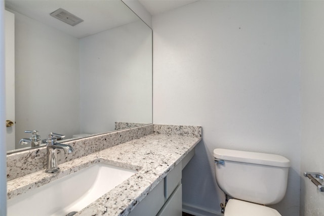 bathroom featuring vanity, toilet, and visible vents
