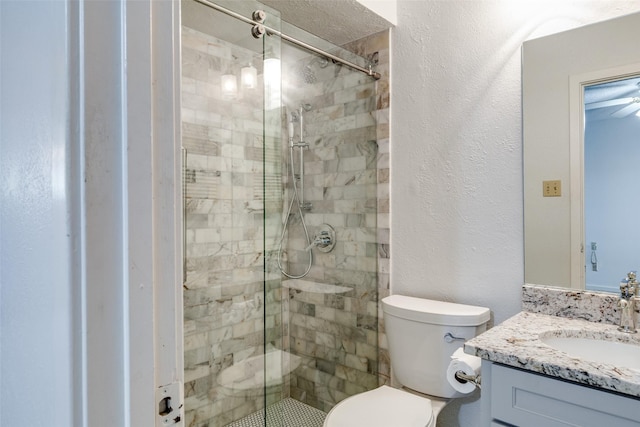 full bath with vanity, toilet, a shower stall, and a textured wall