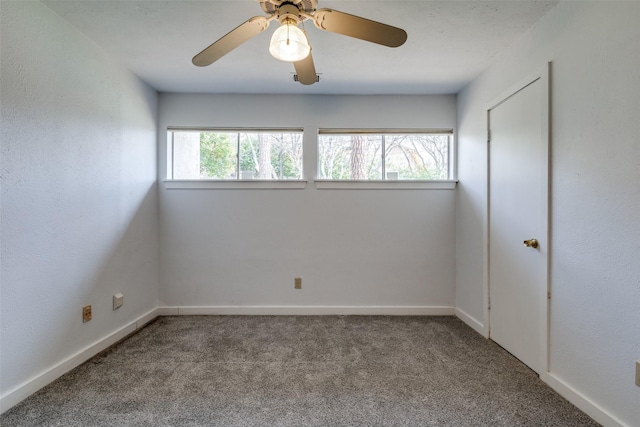 carpeted empty room featuring a ceiling fan and baseboards