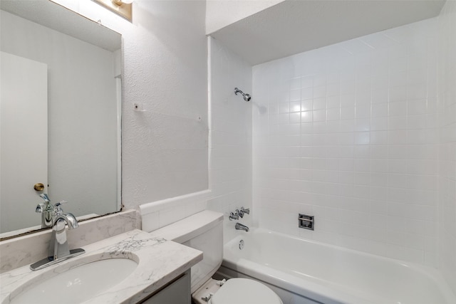bathroom with toilet, bathtub / shower combination, vanity, and a textured wall