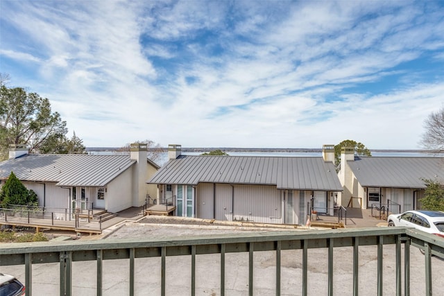 back of property with a chimney, a deck, and metal roof