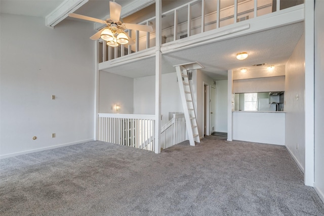 empty room with carpet, a ceiling fan, visible vents, baseboards, and beamed ceiling
