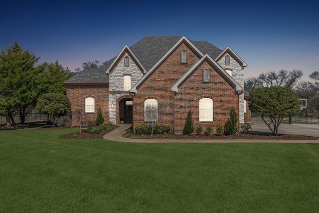 view of front of property with a lawn, brick siding, and stone siding