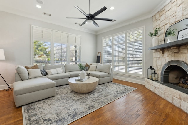 living area featuring a wealth of natural light, visible vents, ornamental molding, and a ceiling fan