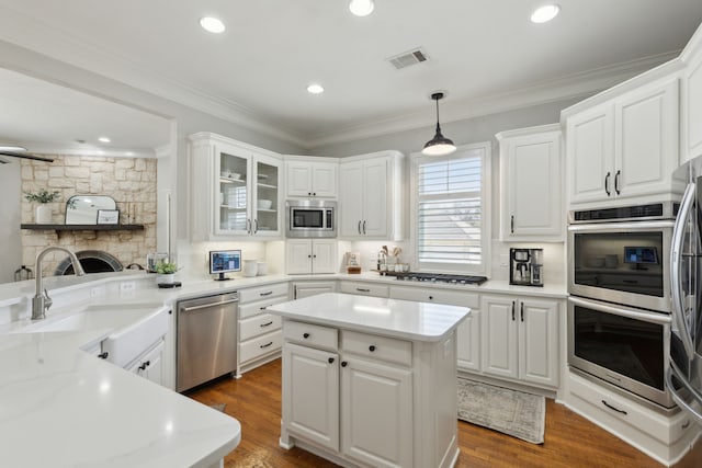 kitchen featuring a sink, stainless steel appliances, visible vents, and ornamental molding