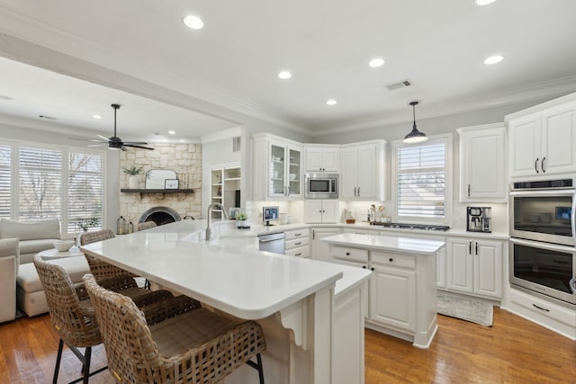 kitchen featuring visible vents, a peninsula, appliances with stainless steel finishes, a kitchen breakfast bar, and open floor plan