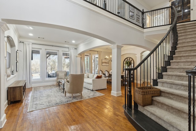 entrance foyer featuring arched walkways, hardwood / wood-style floors, crown molding, and ornate columns