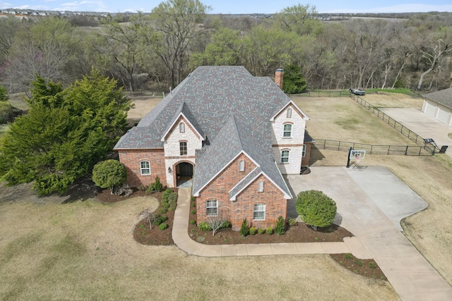 view of front of house with brick siding, fence, concrete driveway, a chimney, and stone siding