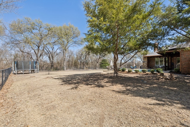 view of yard featuring a trampoline and fence