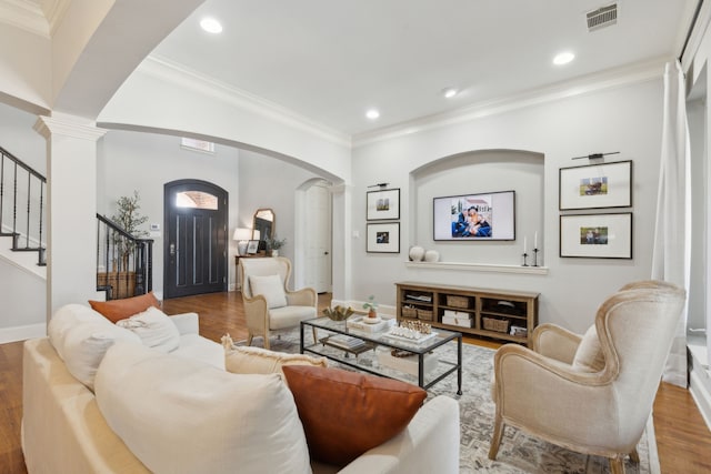 living area with wood finished floors, arched walkways, visible vents, and ornate columns