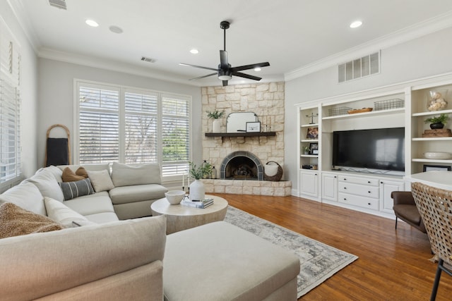 living room with ornamental molding, a fireplace, visible vents, and ceiling fan