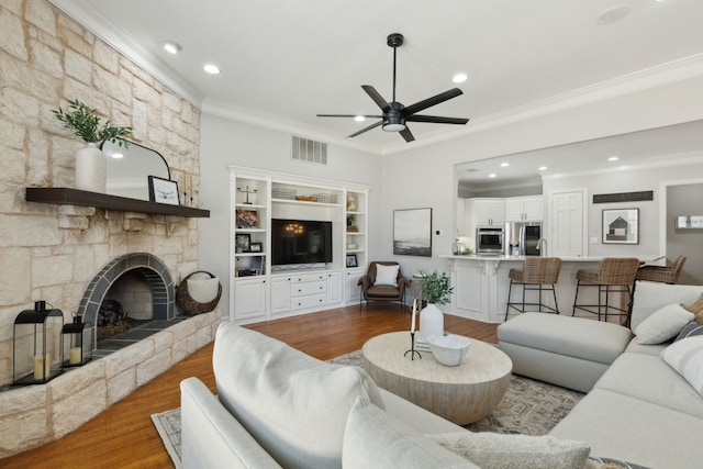 living area with visible vents, ceiling fan, ornamental molding, a fireplace, and dark wood-style flooring