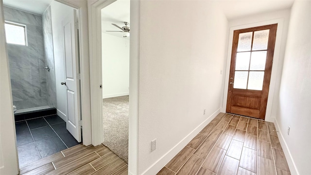 doorway with baseboards, a ceiling fan, and wood tiled floor