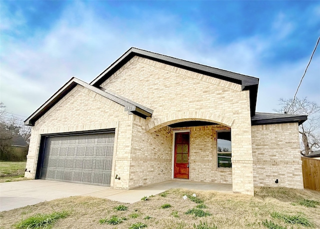 french country home featuring brick siding, an attached garage, and concrete driveway
