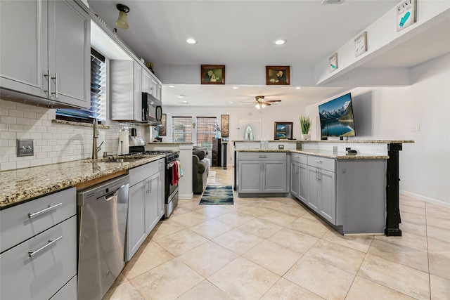 kitchen with backsplash, gray cabinetry, ceiling fan, appliances with stainless steel finishes, and light tile patterned flooring