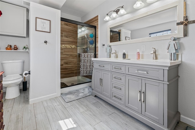 full bath with double vanity, toilet, baseboards, and a stall shower