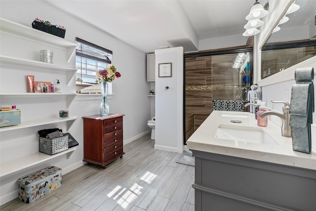 bathroom featuring double vanity, toilet, wood finish floors, and a sink