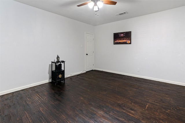 spare room featuring baseboards, visible vents, dark wood-style flooring, and ceiling fan