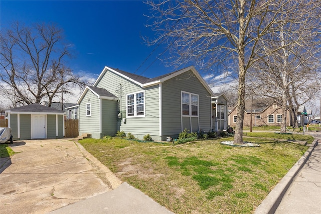 view of side of home with an outbuilding, a lawn, and fence