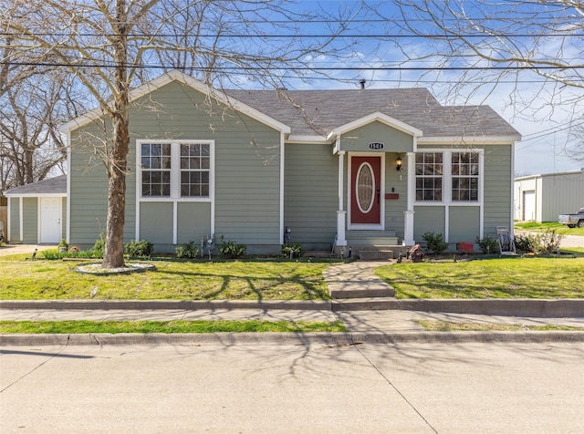 bungalow featuring a front lawn and a shingled roof