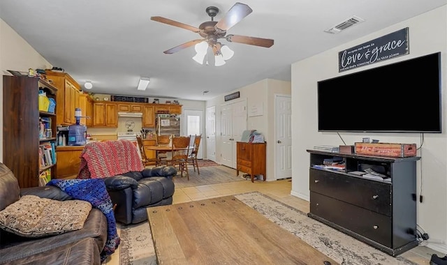 living area with light tile patterned floors, visible vents, baseboards, and a ceiling fan