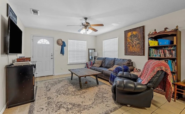 living room with light tile patterned floors, visible vents, and ceiling fan
