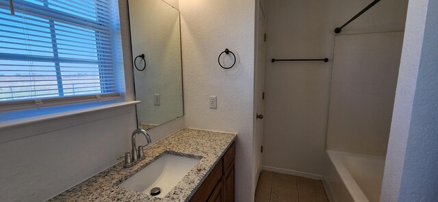 full bath featuring tile patterned floors, shower / washtub combination, baseboards, vanity, and a textured wall