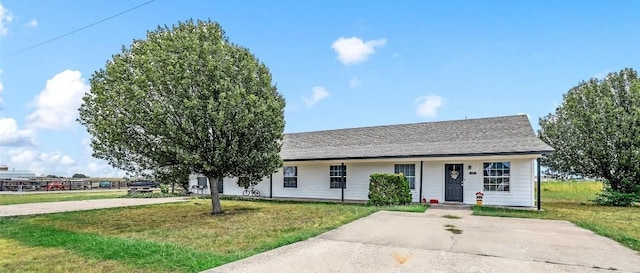 ranch-style home featuring driveway, roof with shingles, and a front yard